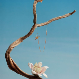 Colgante de libélula de plata bicolor colgado de una rama sobre una flor
